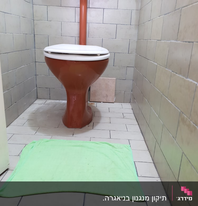 אסלה חומה עם צינור מים על קיר אריחים